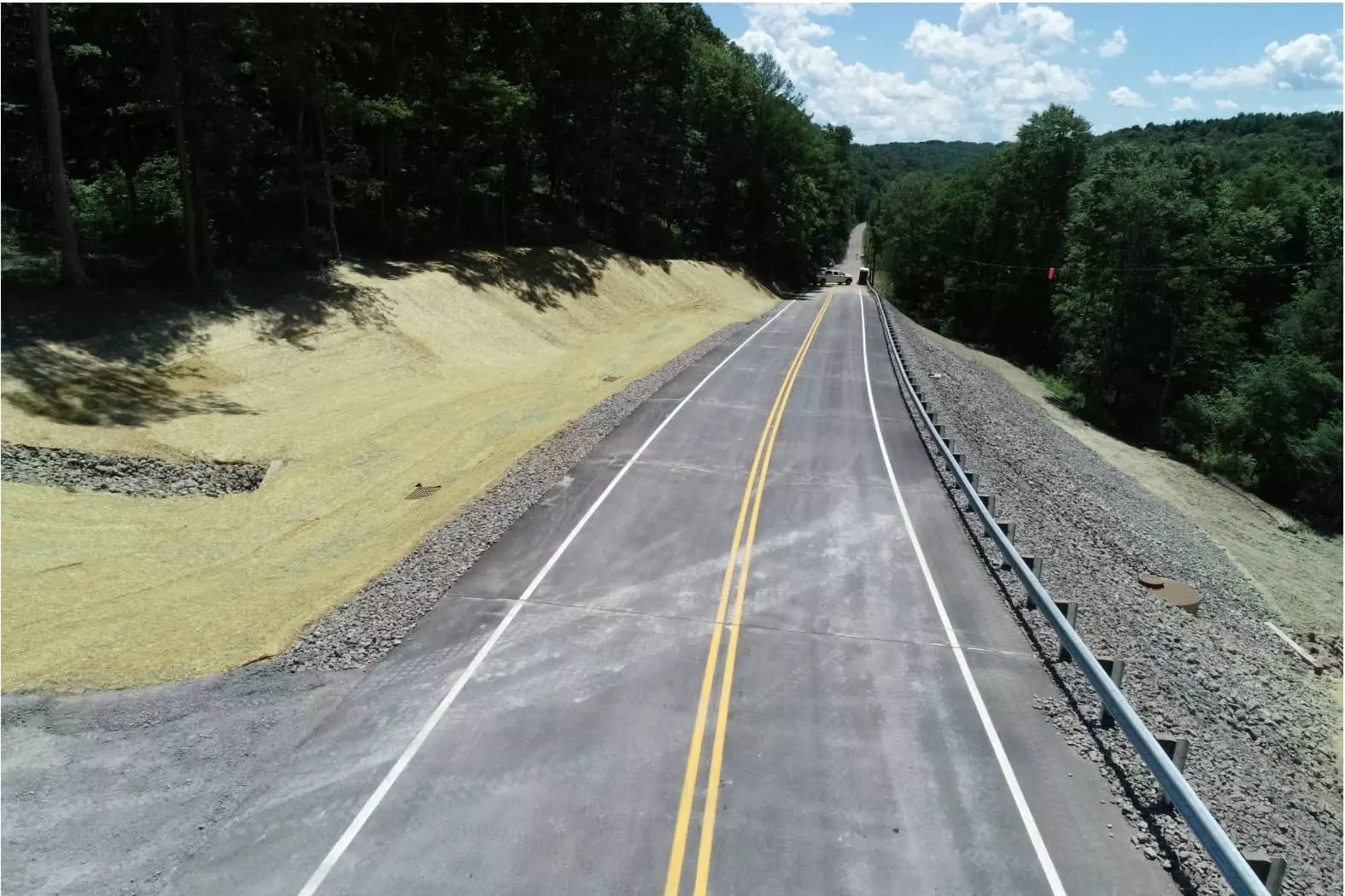 A two-lane highway has ground cover and drainage on either side.